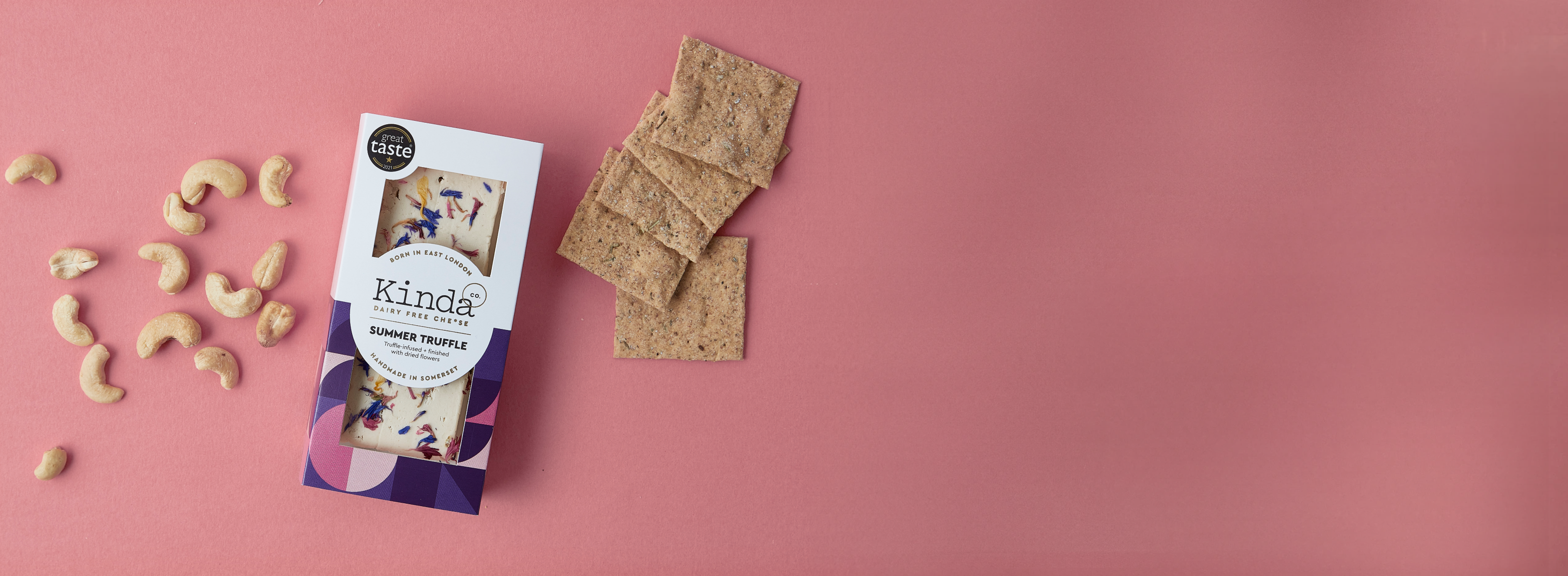 A block of Summer Truffle sits next to a pile of cashews and sourdough crackers