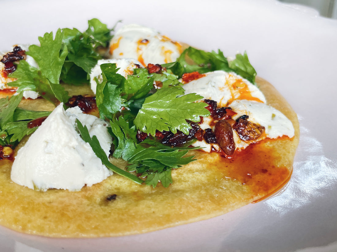 A think savoury pancake topped with cheese, coriander, and chilli oil.