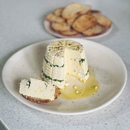 Two pieces of white cheese with green herbs on a plate with a blurred background